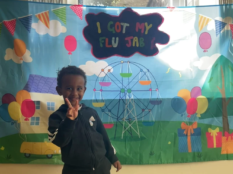 A child standing next to a "I got my flu jab" poster